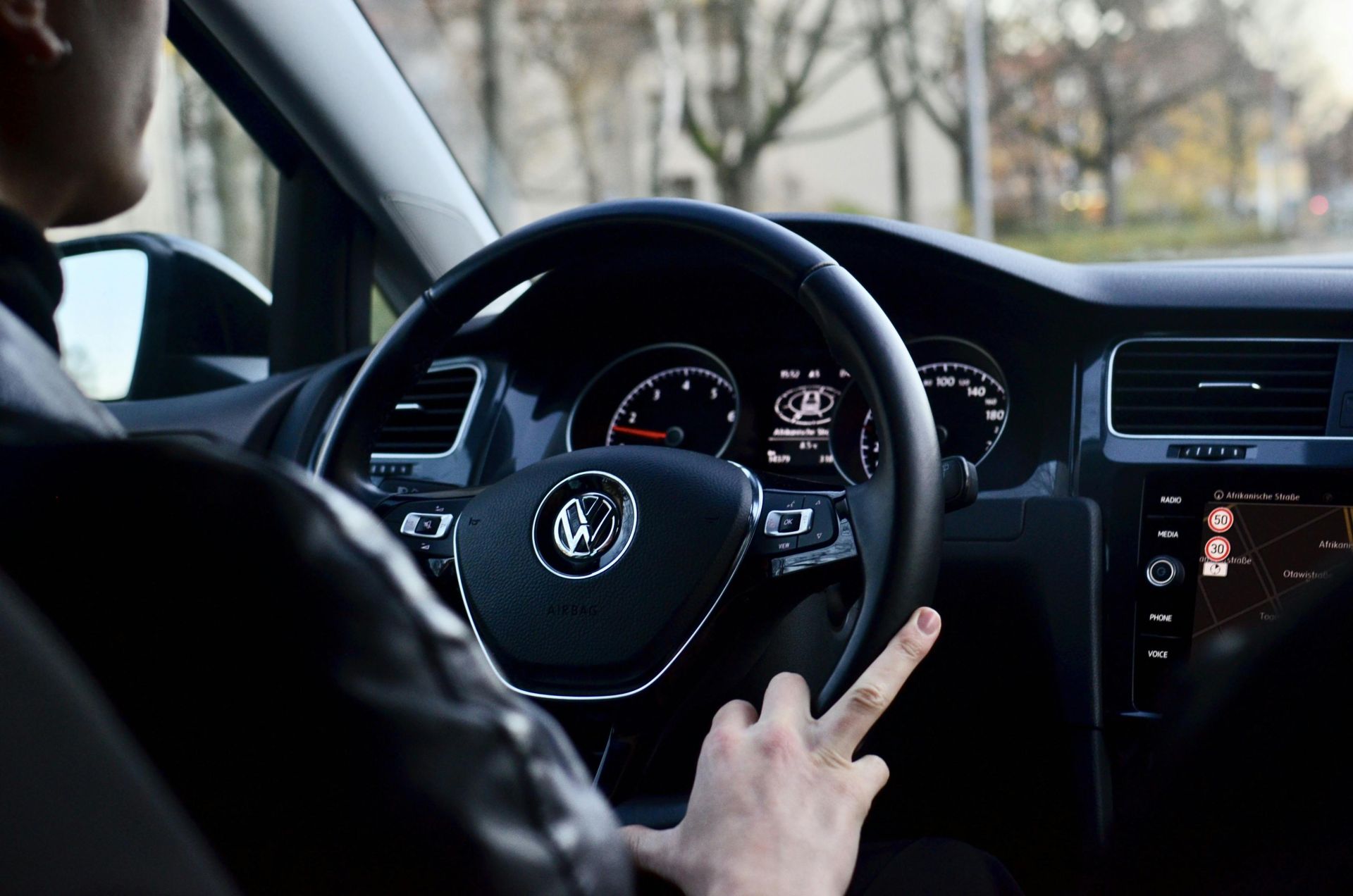 Back view of crop anonymous male driving contemporary transport while turning steering wheel in daylight